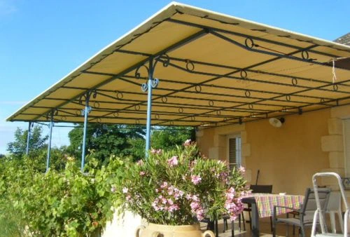 Toile tendue sur pergola en métal noir décoratif, terrasse fleurie avec store sur mesure