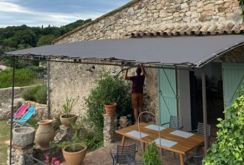 Toile de pergola sur-mesure gris foncé installée sur structure en fer forgé, aménagement terrasse extérieure