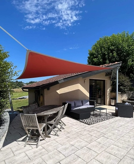 Voile d'ombrage triangulaire installée sur une terrasse pour une protection complète contre le soleil et les intempéries
